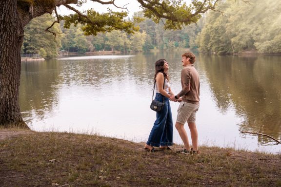 Ăśberraschender Heiratsantrag in der Natur am See mit verliebtem Paar.