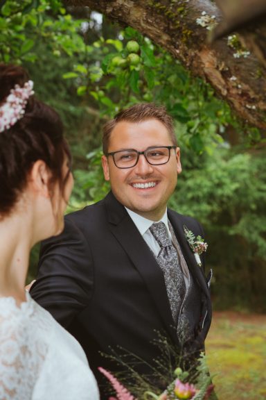 Bräutigam mit Brille lächelt seine Frau an beim First Look in Leonberg