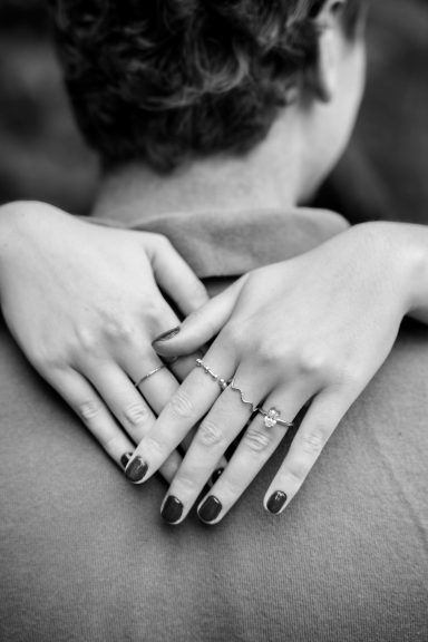 Emotionale Ringaufnahme nach einem Heiratsantrag mit verliebtem Paar im Hintergrund.